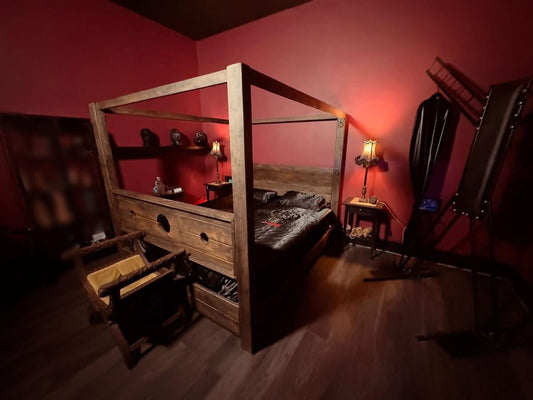 Handmade Three Skulls adult four poster bed with wooden stocks footboard in a red bedroom